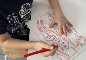 dziecko kalkuje obrazek na transparentnym papierze- przygotowanie do nauki pisania, rysowanie po linii